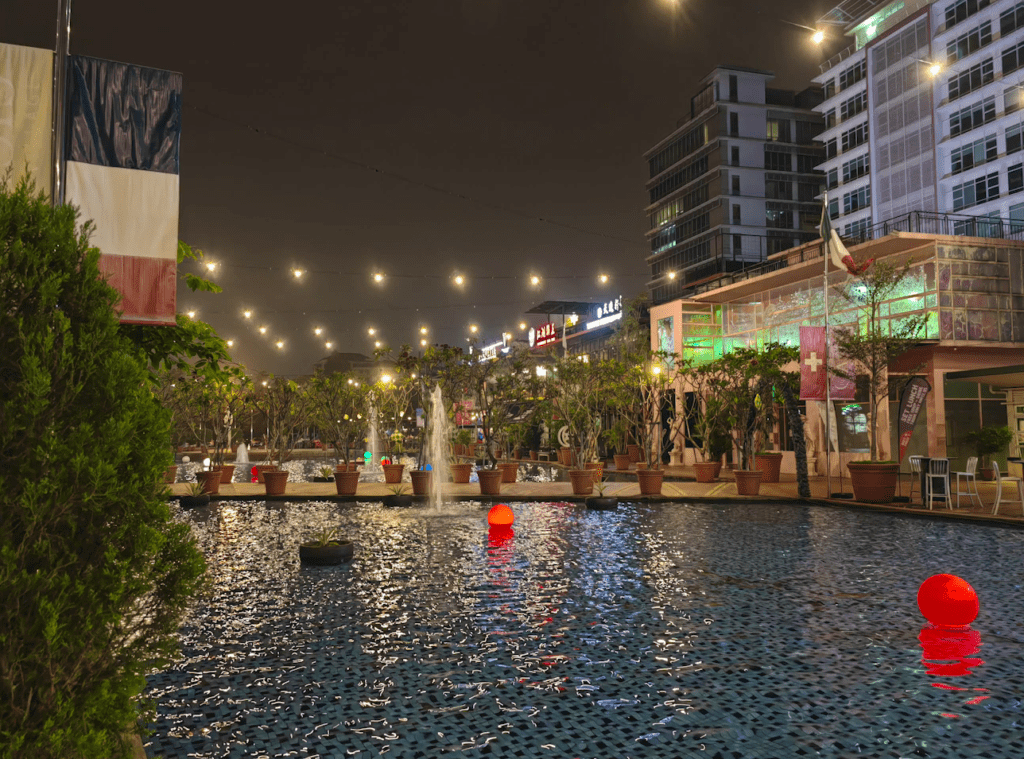 A majestic fountain adorned with vibrant lights, gracefully spouting water against the backdrop of a bustling cityscape at night.