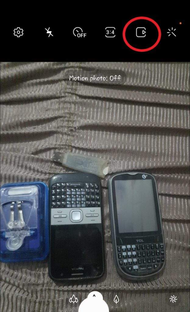 Two Phones One Battery Charger and one Dongle Captured in a phone Camera